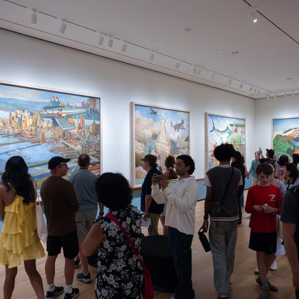 A crowd of people in a gallery with large painted murals