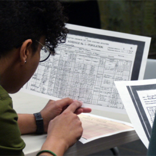 A teacher examines a completed 1900 census form in a workshop comparing the 1900 and 2020 census