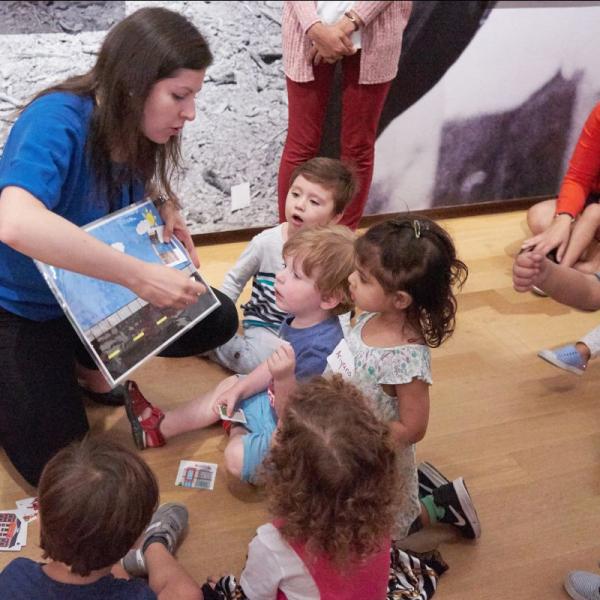 Una mujer lee un libro a un grupo de niños pequeños.