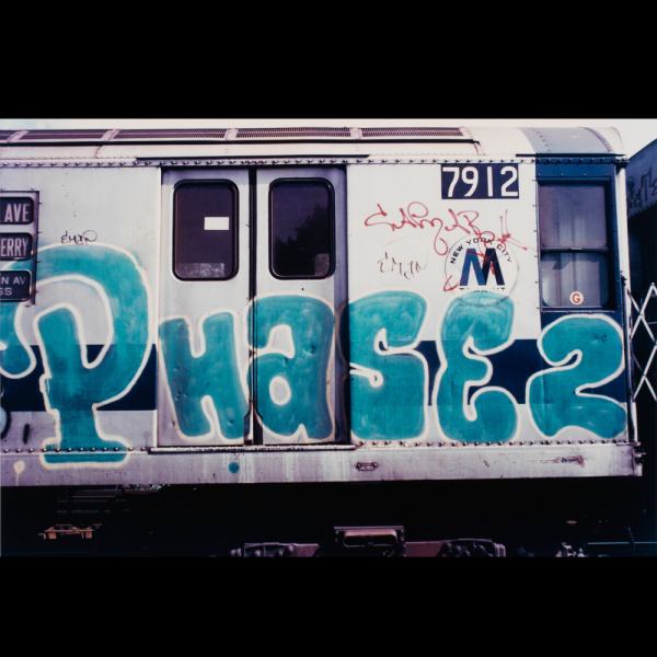 Image of graffiti writing on a subway train car above raised tracks 