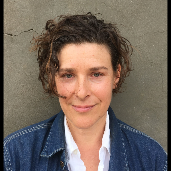 A woman in a denim jacket with short hair smiling