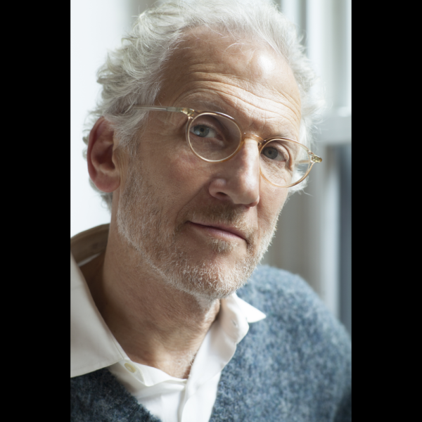 An older man smiling with glasses on