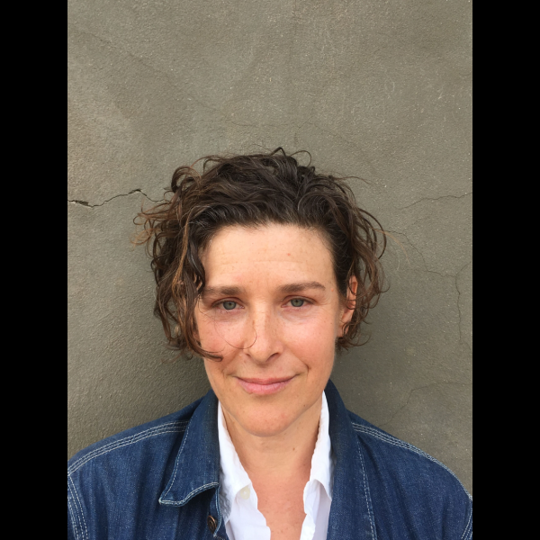 A woman smiling in front of a grey wall