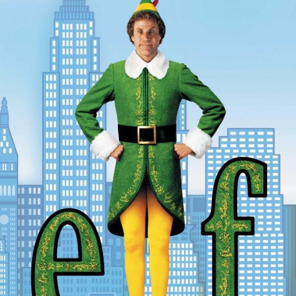 Will Ferrell standing in between the letters “e’ and “f” in a green and yellow “elf” costume with a blue background of a cityscape. 