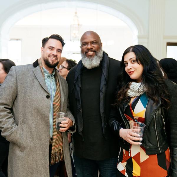 Two men and a woman pose with drinks. 