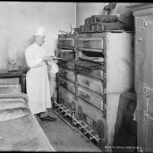 A photo by Wurts Bros. (New York, NY) of a restaurant chef using a bread oven.