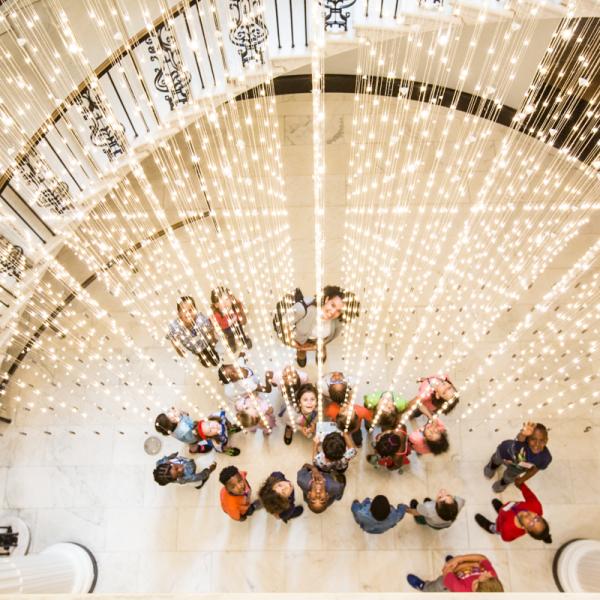 Un groupe d'étudiants se tient sous l'installation lumineuse du Musée, «Starlight».