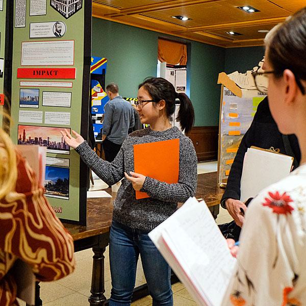 A student explains their project board as History Day judges look on during New York City History Day 2019. 