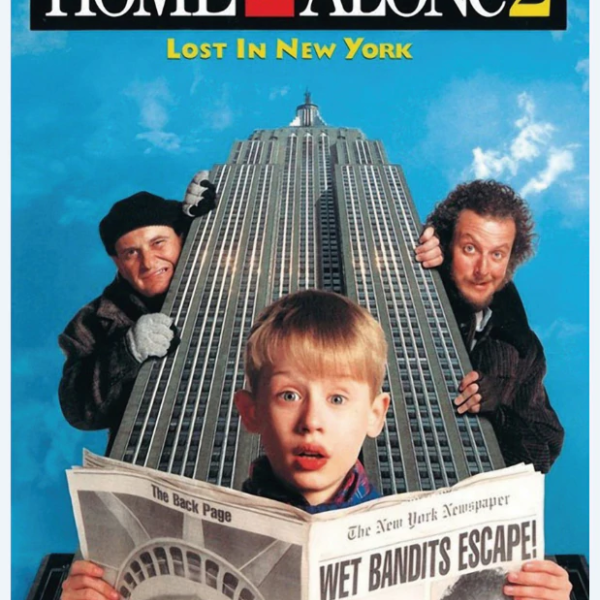 A young boy reading a newspaper in front of the Empire State Building with two men looking from behind the building. 