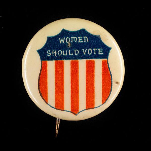 Women’s Suffrage button that says “Women Should Vote” with an image of shield with the red, white, and blue coloring of the American flag. 