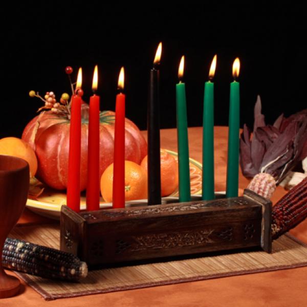 Table set with traditional candle holder, a cup, corn, and gourds.
