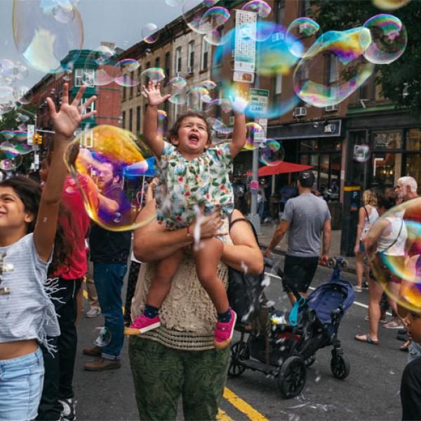 Miembros de la comunidad Park Slope en la calle jugando con burbujas.