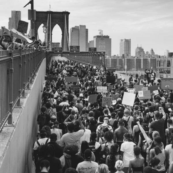 Foto em preto e branco de manifestantes caminhando pela Ponte do Brooklyn