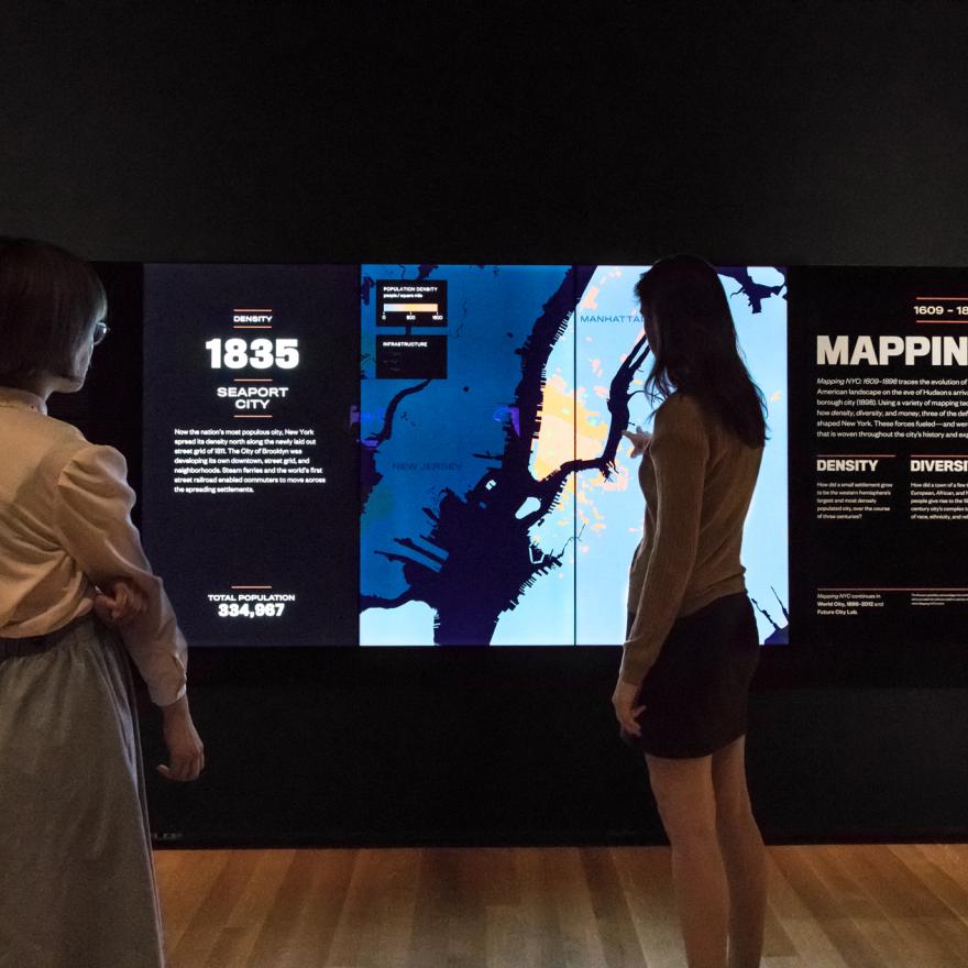 Two visitors look at a changing screen on display in a gallery