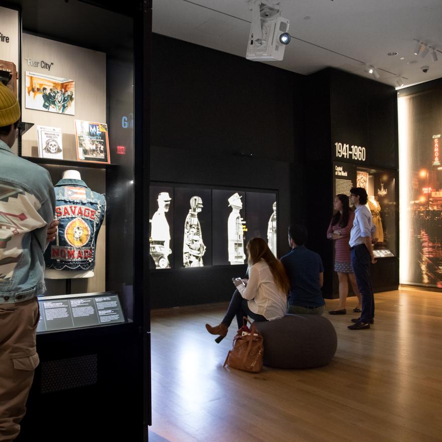 Les visiteurs regardent des objets exposés et des composants numériques interactifs dans une exposition