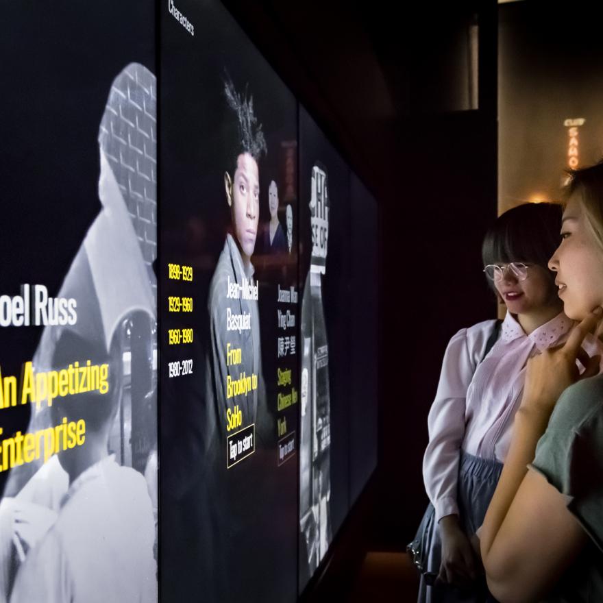 Two visitors look at interactive screens on display in a gallery