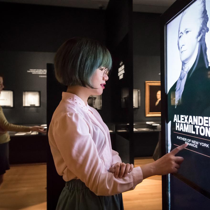 Two visitors examine an interactive feature in an exhibition space