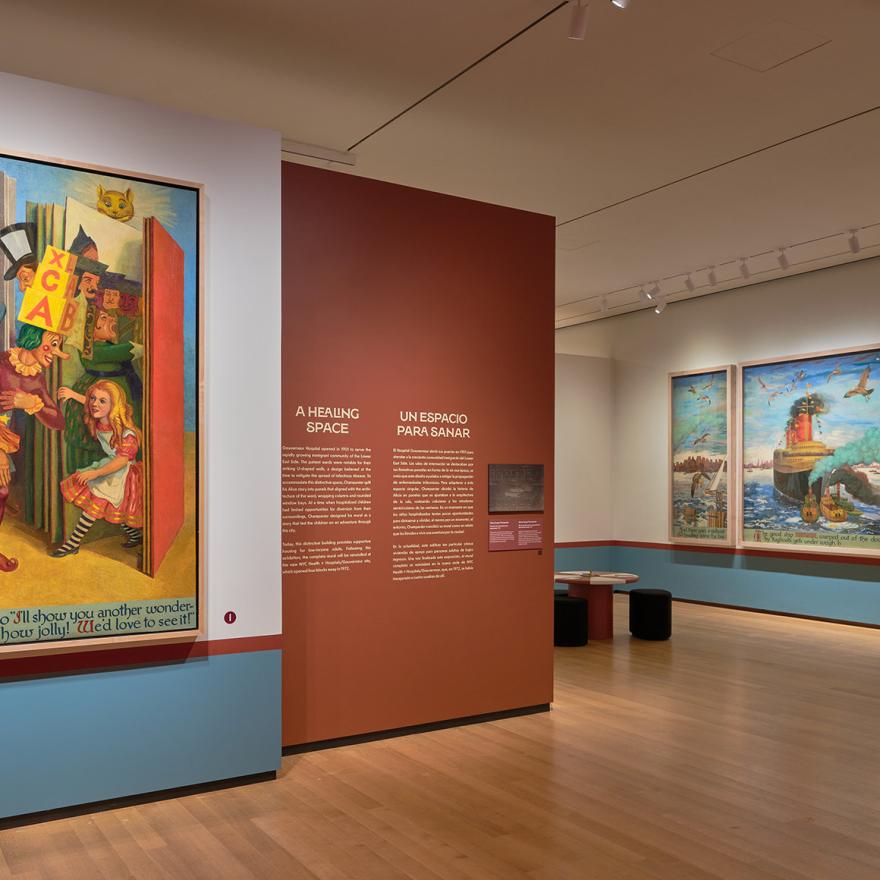 Large mural panels showing Alice and other characters exploring New York City, with red and white tables in the middle of the gallery.