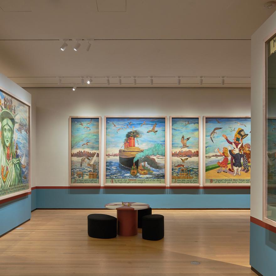 Large mural panels showing Alice and other characters exploring New York City, with red and white tables in the middle of the gallery.