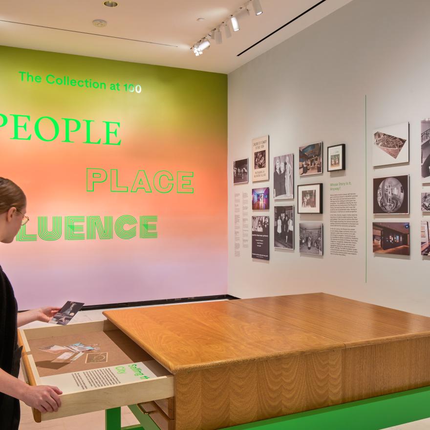 A woman opens a drawer in a gallery. 