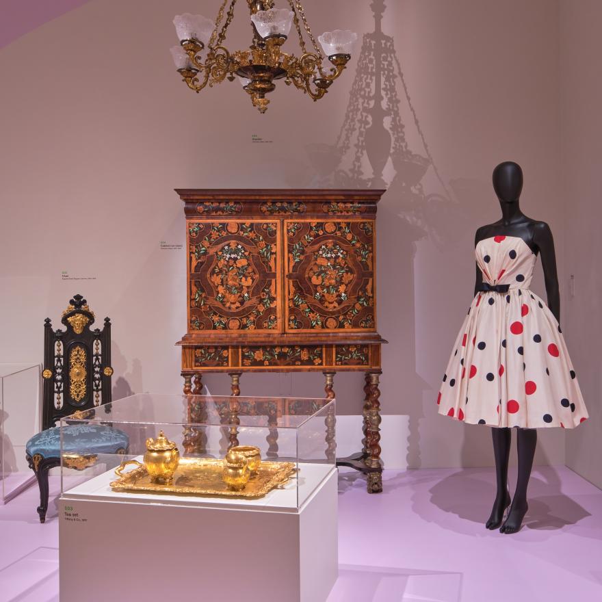 A mannequin and ornate furniture are displayed in a gallery. 