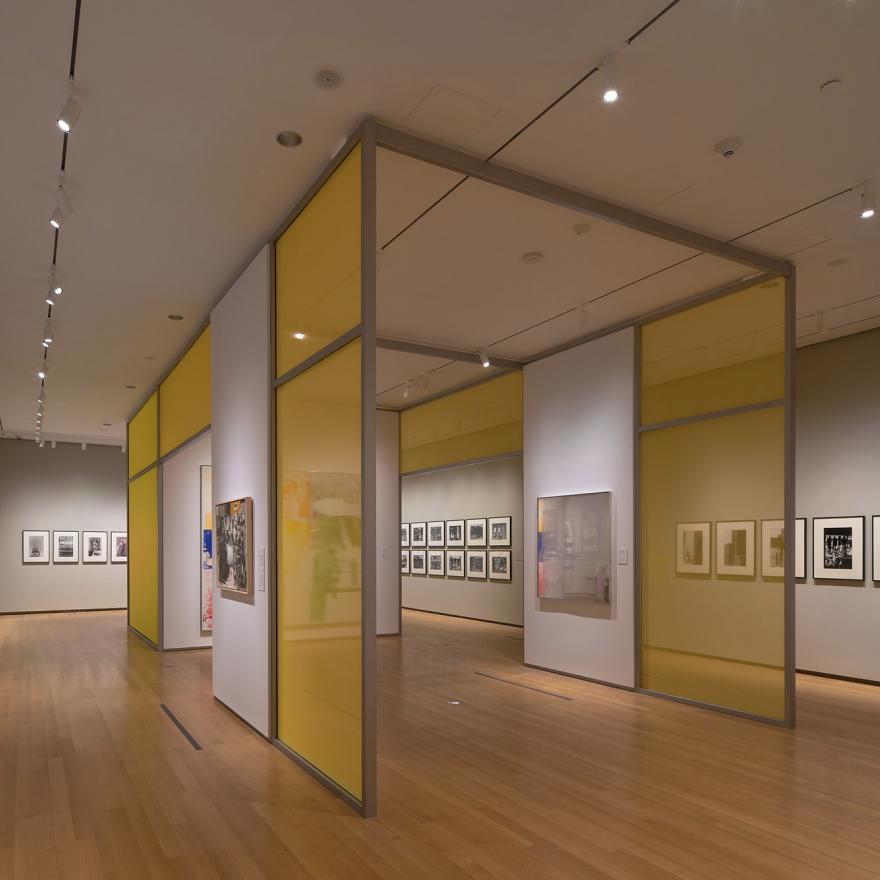 Installation of Robert Rauschenberg’s New York with yellow walls surrounded by photographs