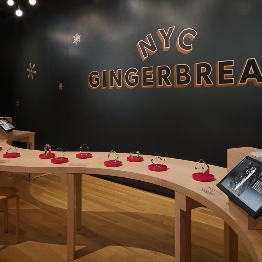 A wavy wooden table in front of a sign reading, "Gingerbread NYC"