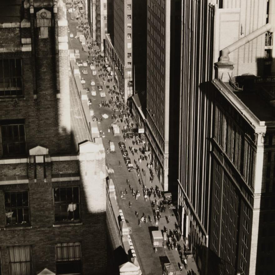 View of a street in New York City that’s surrounded on both sides by tall buildings, creating a “canyon” with the street