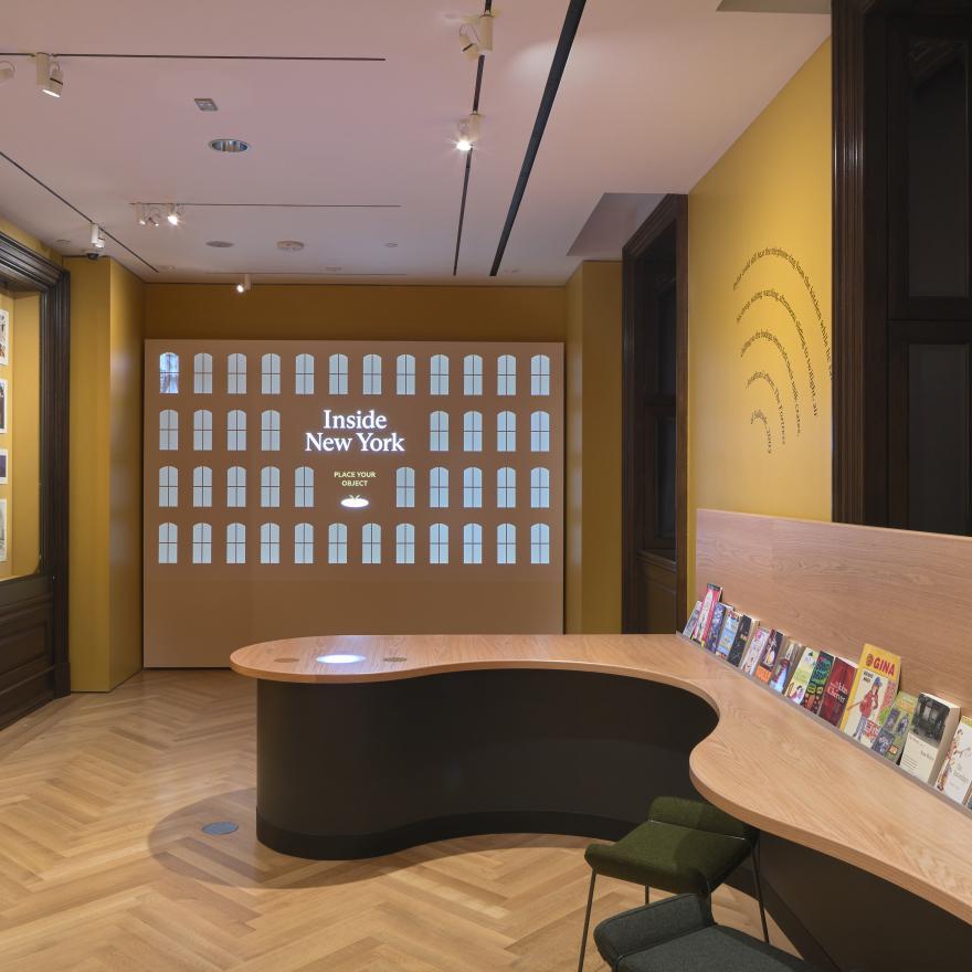 A wall display in a gallery with books lined up on a wall. 