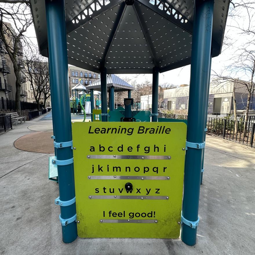 Fotografía en color de un panel Braille en un parque infantil.