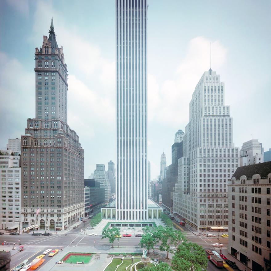 Un edificio se eleva sobre sus vecinos, ya que ocupa un bloque completo en la ciudad de Nueva York. En frente del edificio hay un parque