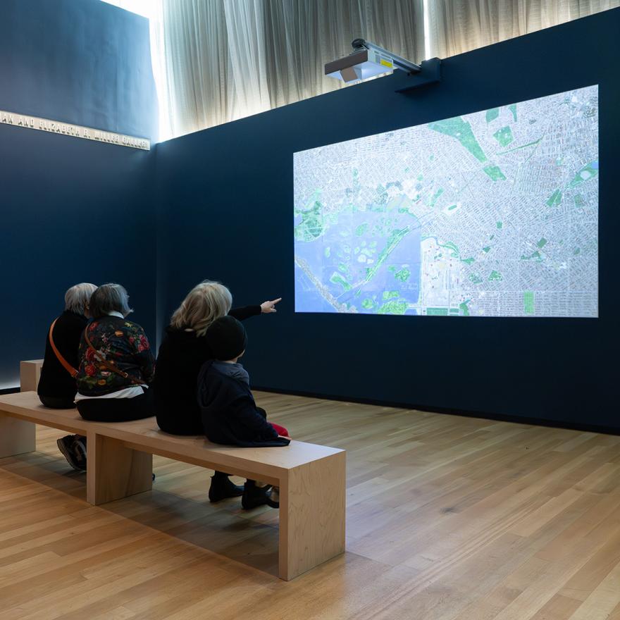 A few people sitting on a bench watching a projected video