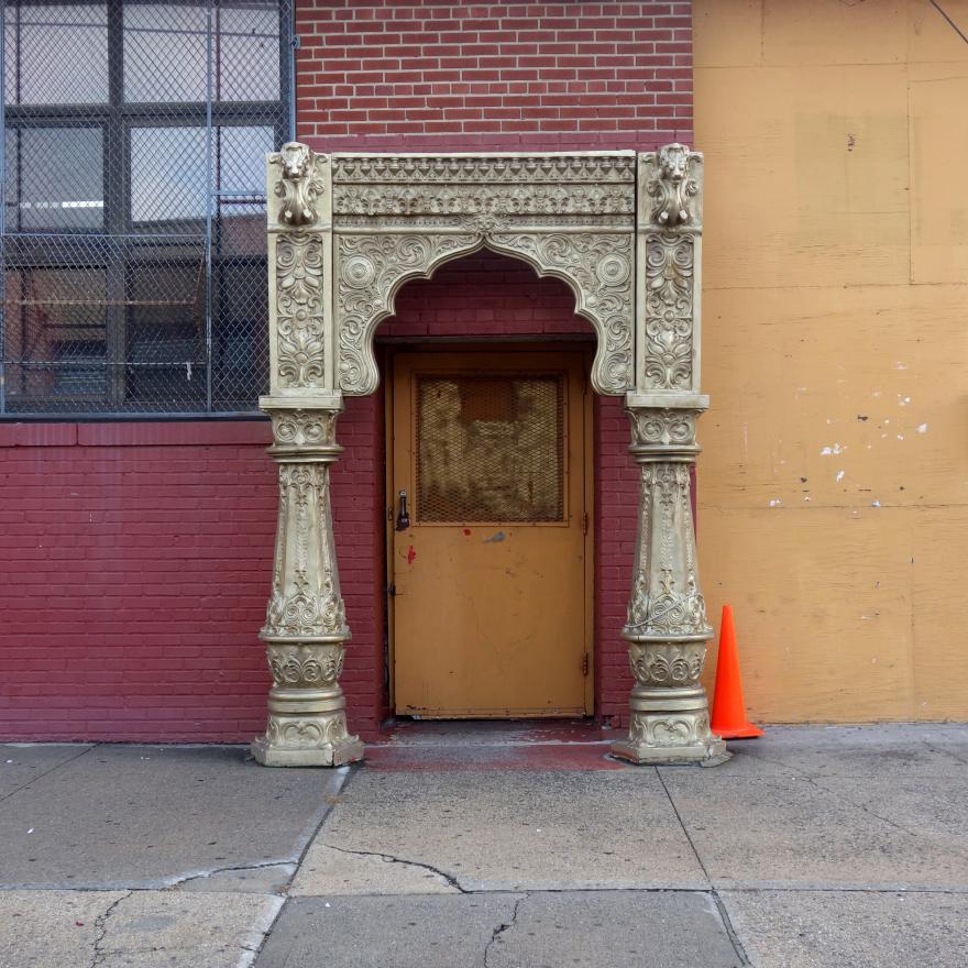 A view of an industrial building in the background with an archway placed in front of it.  