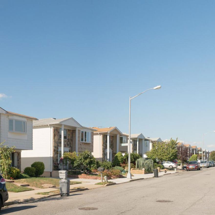 Uma série de casas idênticas de dois andares se alinha em uma rua