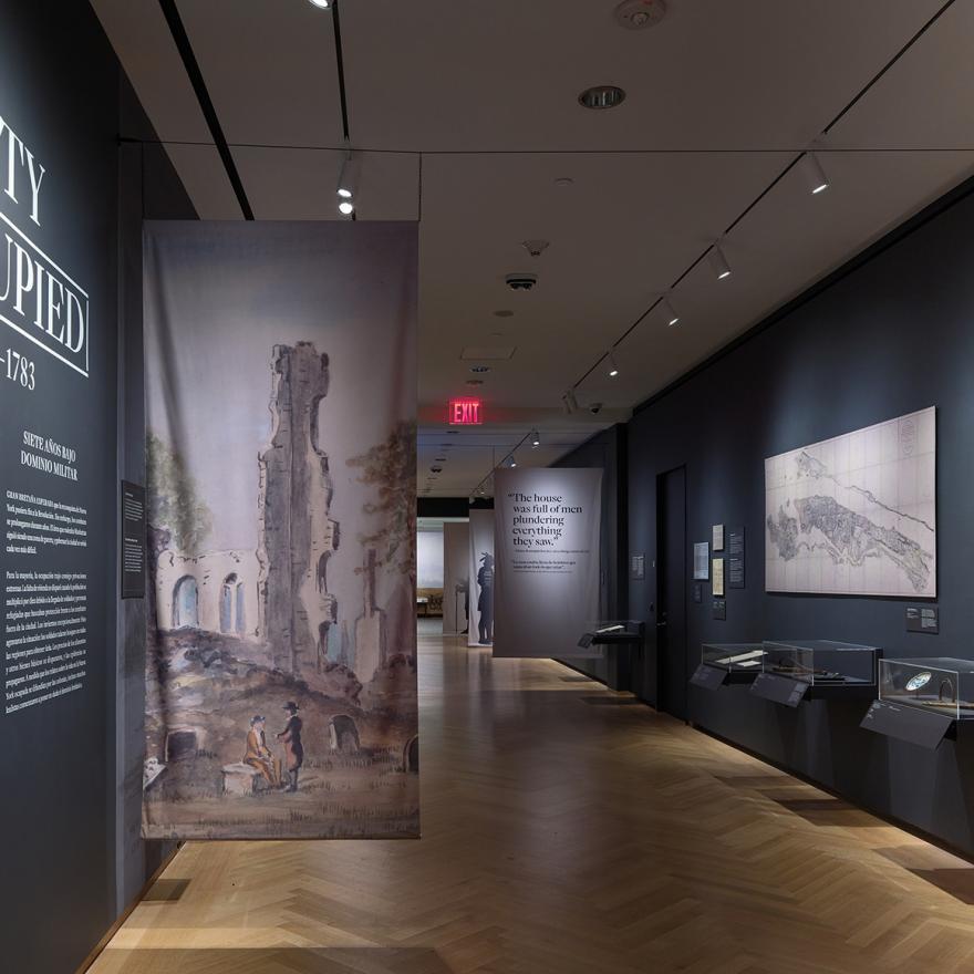 Installation view of the galleries, showing hanging banners, artwork on the walls, and wall text saying, “City Occupied.”