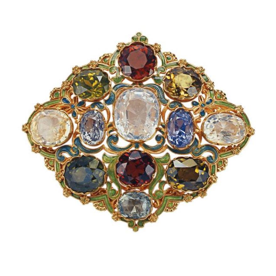 Brooch made of metal, painted green and teal with gold pieces and edges. A number of large gemstones are set in the metal