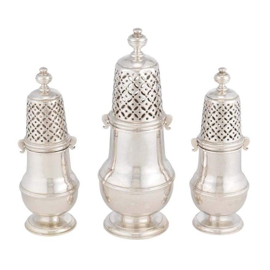 Three silver sugar casters, objects used like salt shakers for sugar. The middle caster is larger than the other two