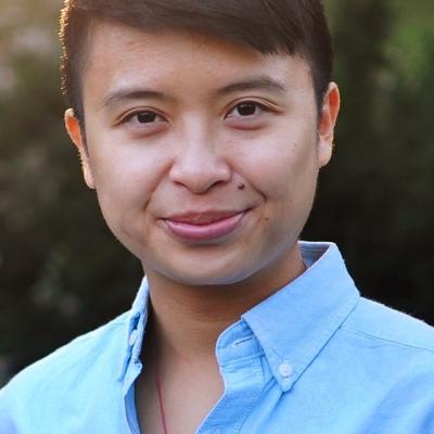 A photograph of poet and scholar huiying b. chan. huiying wears a blue shirt and is standing in the sun.