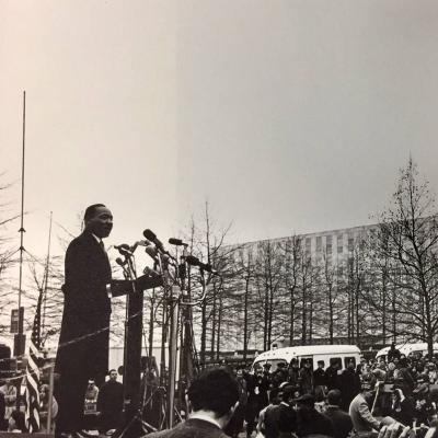 From an elevated platform, Rev. Martin Luther King Jr. addresses a gathered crowd of journalists in New York City