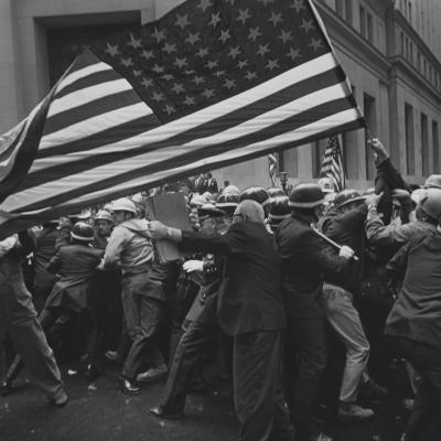 A crowd of protesters at a Pro-Vietnam-War demonstration holding a large American flag