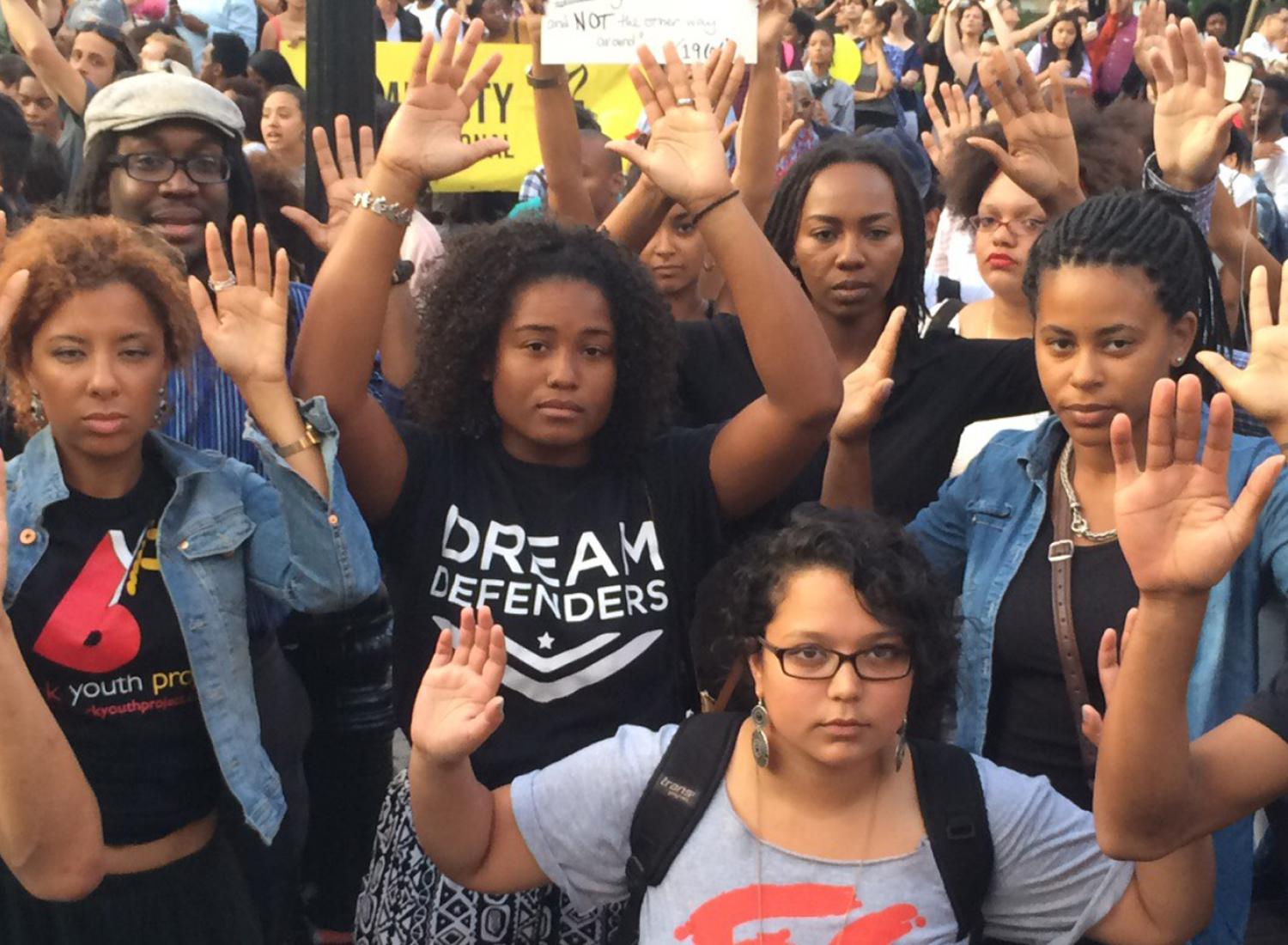 Black Lives Matter protesters with their hands in the air in a sign of surrender and the “hands up don’t shoot” slogan