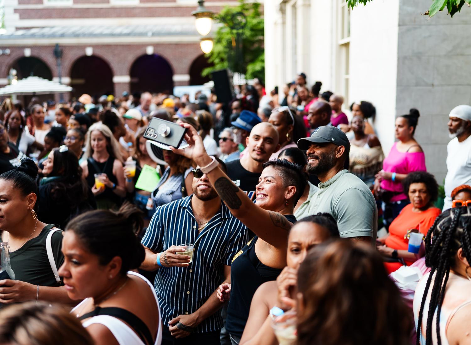 A crowd of people outside of the Museum of the City of New York and four people taking a selfie.