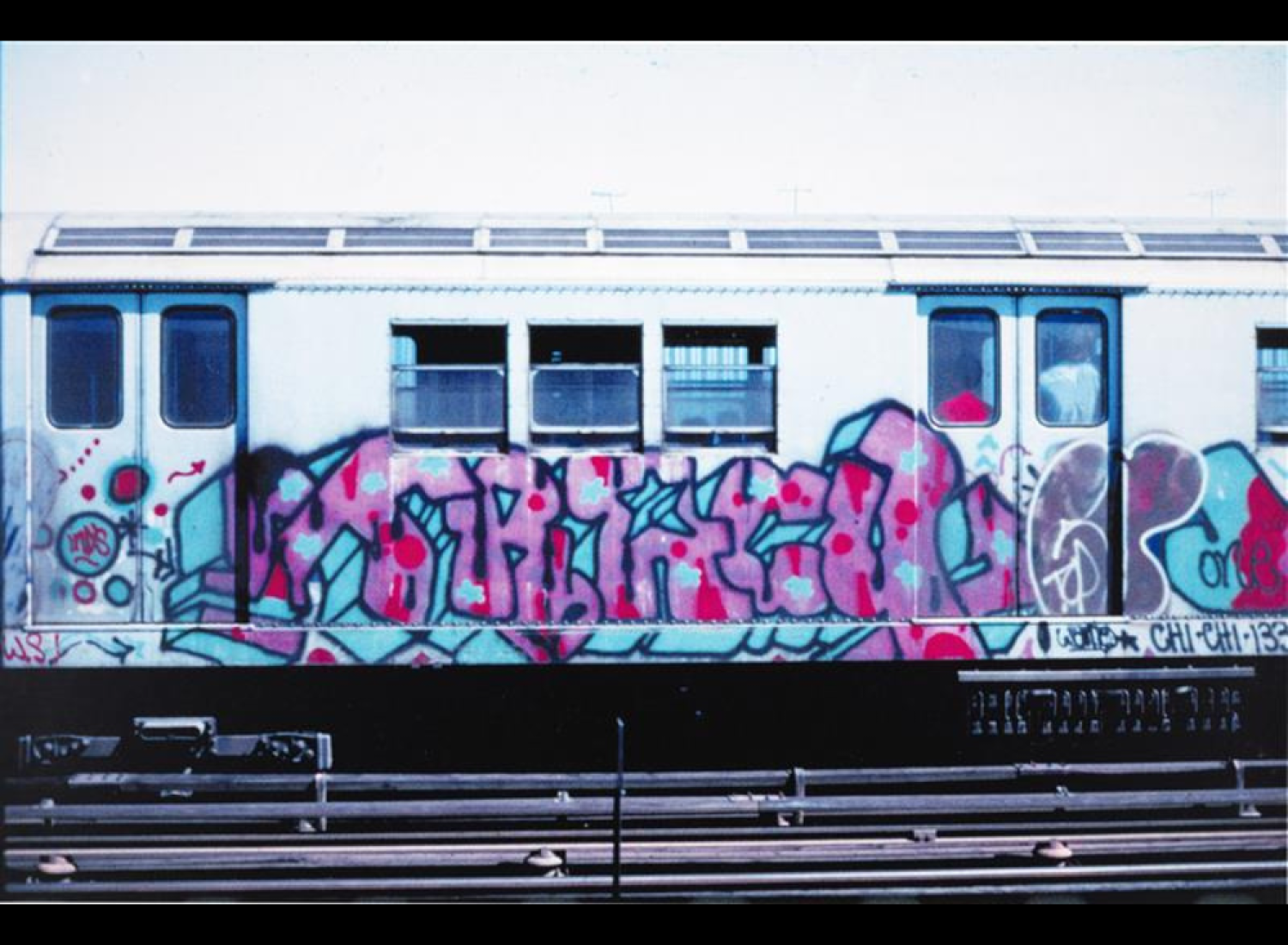Image of Graffiti writing on a subway car on outdoor train tracks