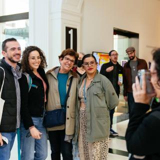 Un groupe d'hommes et de femmes se rassemblent pour se faire prendre en photo par une autre femme.