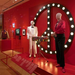 Mannequins wearing festive clothing in front of a peace sign 