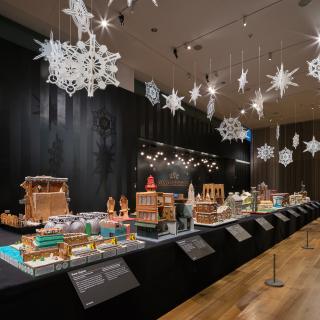 A long table with gingerbread houses inspired by New York, with lights and snowflakes hanging above