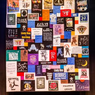 An image of a quilt with multiple colorful rectangular patches with people dancing and words like "Frankie Manning" and "Savoy"