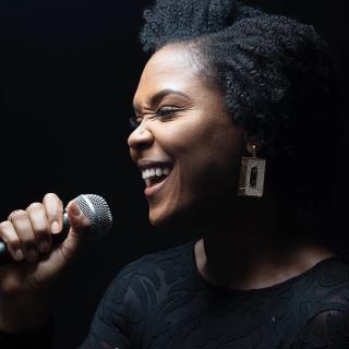 Black background image of Shanelle Gabriel holding microphone