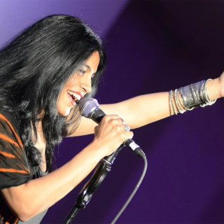 Image of singer Falu holding microphone singing with purple background
