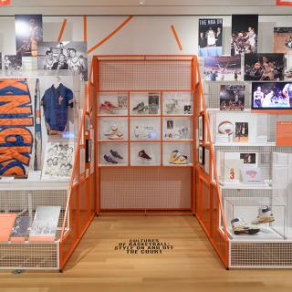 Installation photo of the City/Game exhibit, featuring sneakers, basketball jerseys, and photographs of basketball players. 